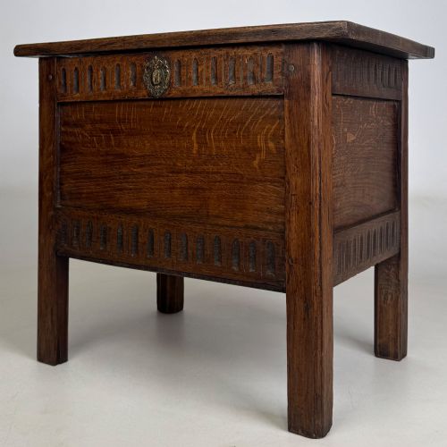 fig 1. An 18th-century small oak coffer chest featuring carved vertical fluting along the top and bottom rails, a central decorative brass escutcheon, and straight squared legs.