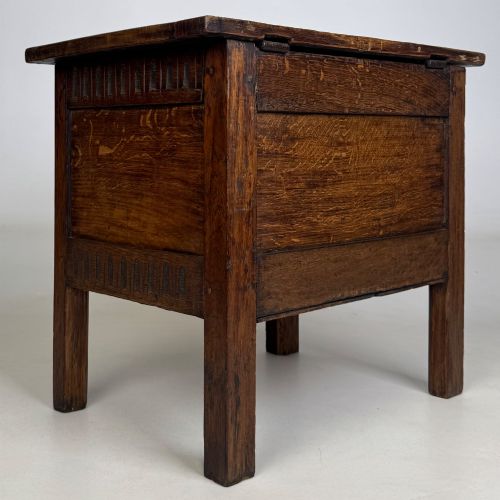 fig 3. An 18th-century small oak coffer chest featuring carved vertical fluting along the top and bottom rails, a central decorative brass escutcheon, and straight squared legs.