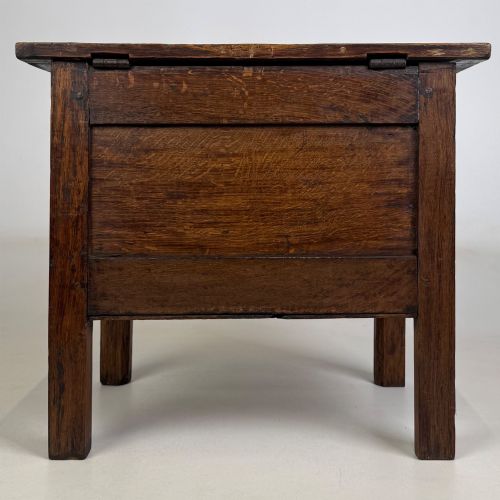 fig 4. An 18th-century small oak coffer chest featuring carved vertical fluting along the top and bottom rails, a central decorative brass escutcheon, and straight squared legs.