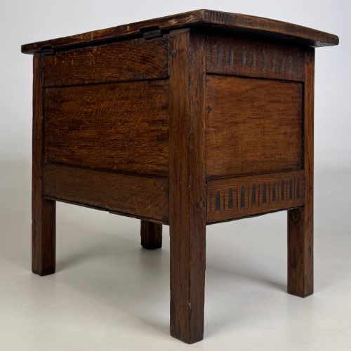 fig 5. An 18th-century small oak coffer chest featuring carved vertical fluting along the top and bottom rails, a central decorative brass escutcheon, and straight squared legs.