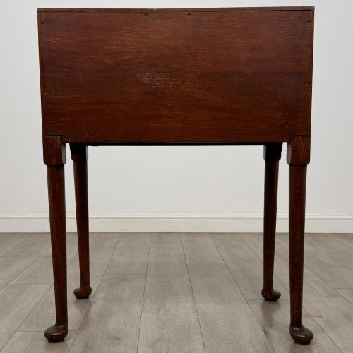 fig 5. A golden oak slant-front writing bureau standing on four slender legs with pad feet, featuring a single lower drawer with drop handles and a hinged writing slope.