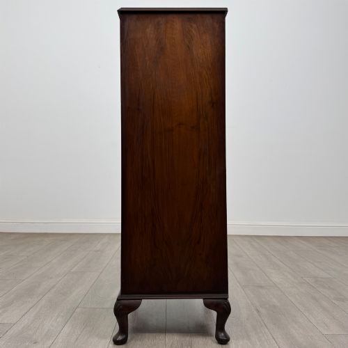 fig 2. A tall, narrow dark brown burr walnut chest of drawers featuring brass handles and carved cabriole legs.