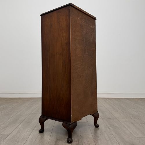 fig 3. A tall, narrow dark brown burr walnut chest of drawers featuring brass handles and carved cabriole legs.