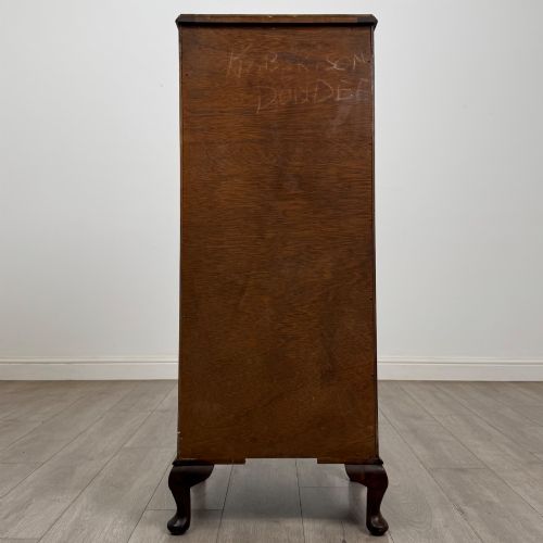 fig 4. A tall, narrow dark brown burr walnut chest of drawers featuring brass handles and carved cabriole legs.