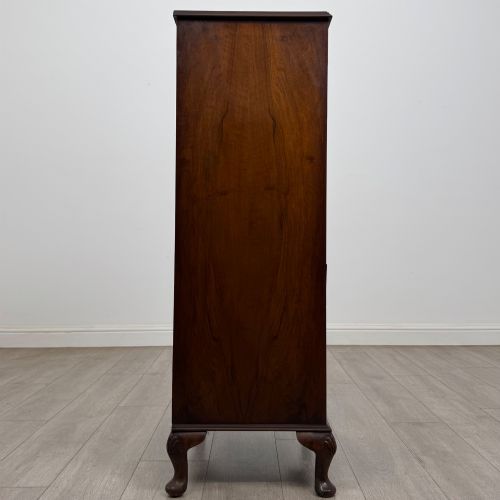 fig 6. A tall, narrow dark brown burr walnut chest of drawers featuring brass handles and carved cabriole legs.
