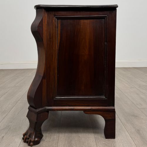 fig 2. A small 20th-century Dutch bombe chest of drawers made from polished brown wood with three drawers, brass handles, and carved claw feet.