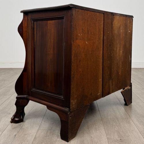 fig 3. A small 20th-century Dutch bombe chest of drawers made from polished brown wood with three drawers, brass handles, and carved claw feet.
