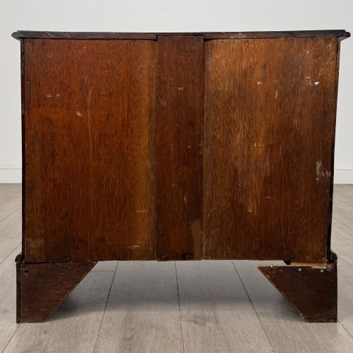 fig 4. A small 20th-century Dutch bombe chest of drawers made from polished brown wood with three drawers, brass handles, and carved claw feet.