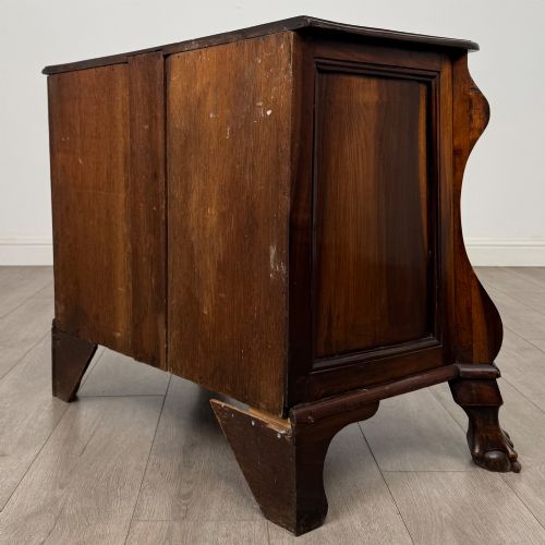 fig 5. A small 20th-century Dutch bombe chest of drawers made from polished brown wood with three drawers, brass handles, and carved claw feet.