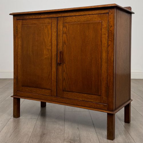 fig 2. An Edwardian warm brown oak fitted cupboard featuring twin recessed panel doors, a central wooden latch, and four straight legs.