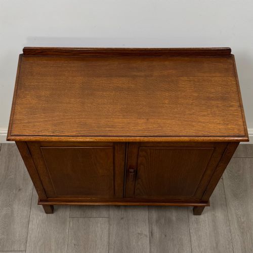 fig 9. An Edwardian warm brown oak fitted cupboard featuring twin recessed panel doors, a central wooden latch, and four straight legs.