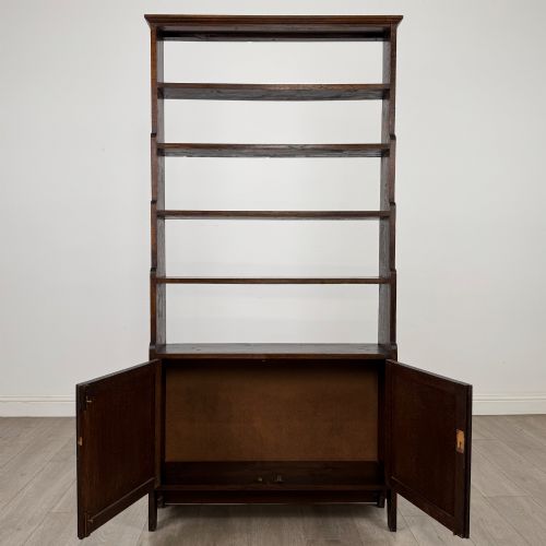 fig 2. A tall dark oak open bookcase featuring multiple upper shelves and a two-door lower cupboard base.