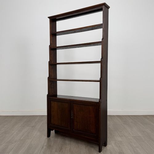 fig 3. A tall dark oak open bookcase featuring multiple upper shelves and a two-door lower cupboard base.