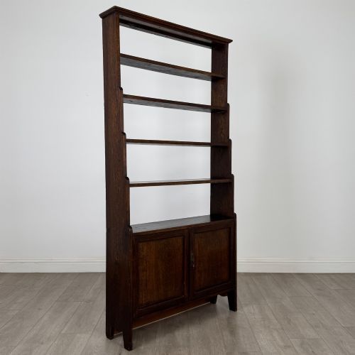fig 9. A tall dark oak open bookcase featuring multiple upper shelves and a two-door lower cupboard base.