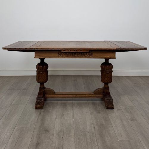 fig 1. An antique Edwardian oak draw-leaf dining table featuring carved bulbous supports and a central stretcher.