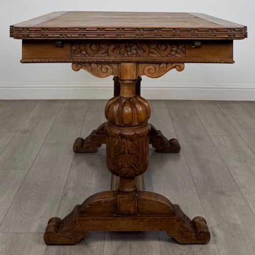 fig 2. An antique Edwardian oak draw-leaf dining table featuring carved bulbous supports and a central stretcher.