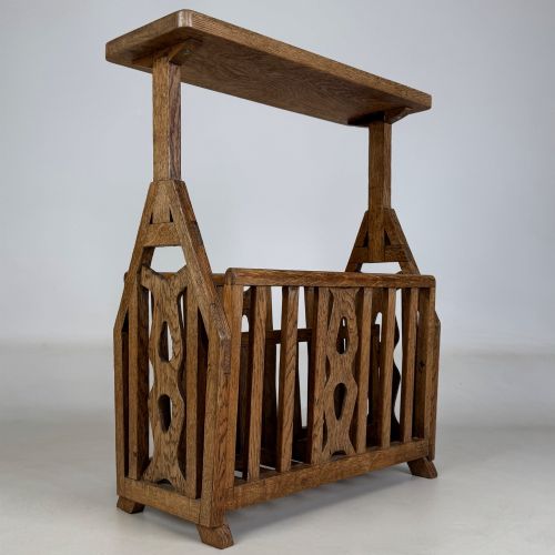 fig 3. An antique Arts and Crafts oak side table featuring a rectangular top supported by slender uprights above a slatted lower magazine trough.