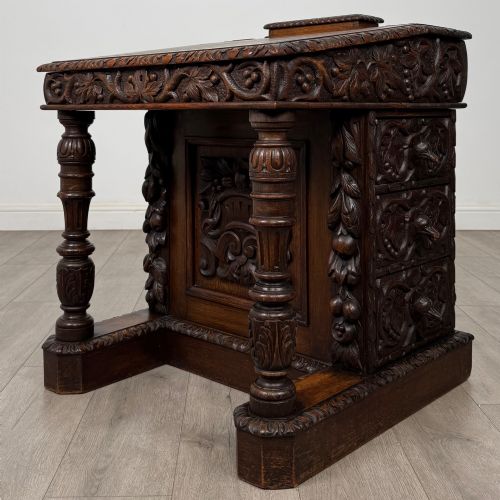 fig 1. A 19th-century Victorian carved oak davenport desk featuring heavy foliate carvings, turned columns, and a green leather insert.