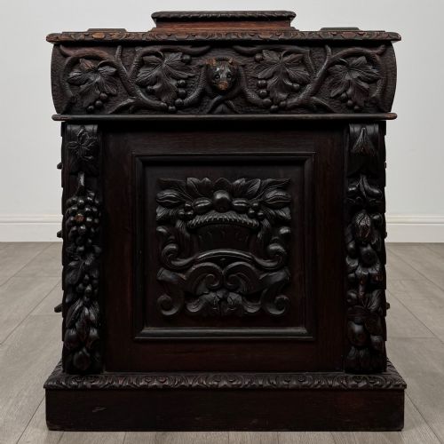 fig 4. A 19th-century Victorian carved oak davenport desk featuring heavy foliate carvings, turned columns, and a green leather insert.