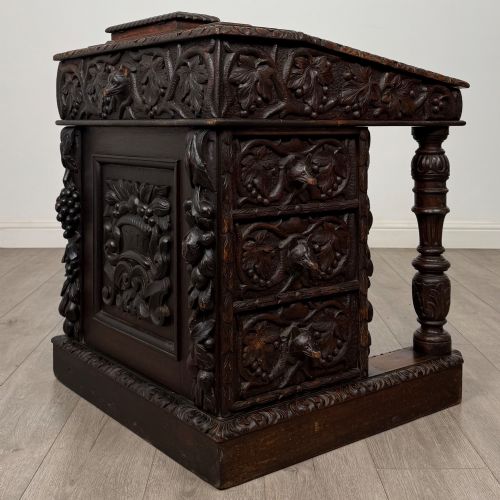fig 5. A 19th-century Victorian carved oak davenport desk featuring heavy foliate carvings, turned columns, and a green leather insert.