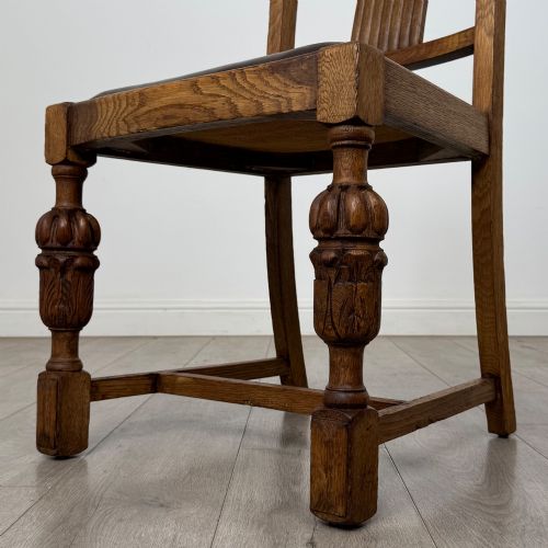 fig 4. A set of four Edwardian oak dining chairs featuring carved back splats, brown upholstered seats, and bulbous turned front legs.