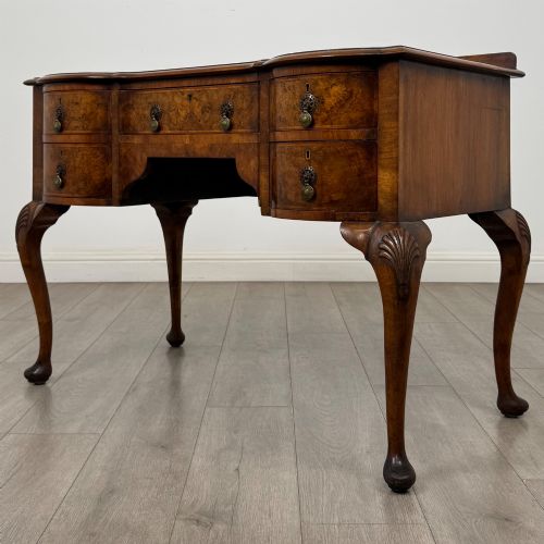 fig 1. An Edwardian burr walnut writing table featuring five drawers with brass drop handles and carved cabriole legs.