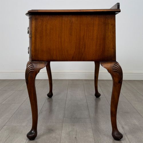 fig 2. An Edwardian burr walnut writing table featuring five drawers with brass drop handles and carved cabriole legs.