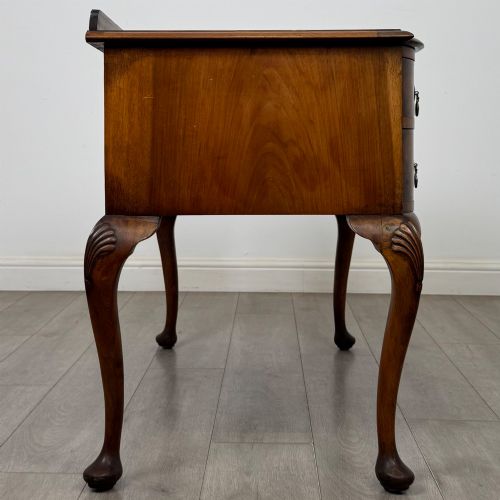 fig 6. An Edwardian burr walnut writing table featuring five drawers with brass drop handles and carved cabriole legs.