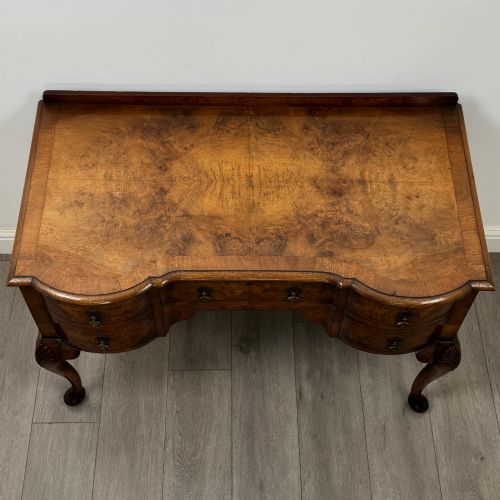 fig 8. An Edwardian burr walnut writing table featuring five drawers with brass drop handles and carved cabriole legs.
