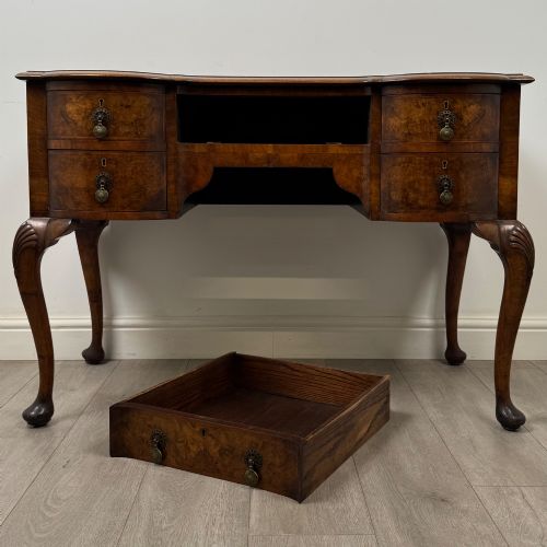 fig 9. An Edwardian burr walnut writing table featuring five drawers with brass drop handles and carved cabriole legs.