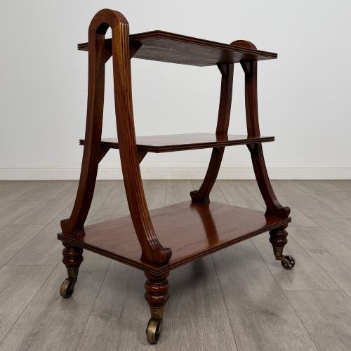 fig 2. A three-tiered mahogany trolley featuring arched reeded side supports and turned feet resting on brass castors.