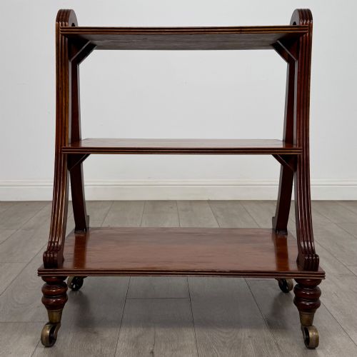 fig 3. A three-tiered mahogany trolley featuring arched reeded side supports and turned feet resting on brass castors.