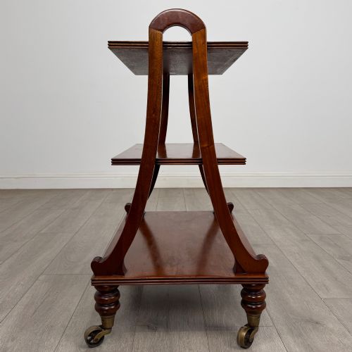 fig 5. A three-tiered mahogany trolley featuring arched reeded side supports and turned feet resting on brass castors.