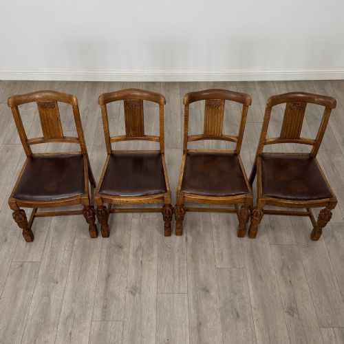 fig 6. An early twentieth-century oak dining table featuring carved frieze detailing and heavy turned legs, shown alongside four matching oak dining chairs with dark leather seats.