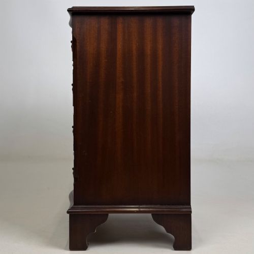 fig 2. A small mahogany chest of four drawers featuring flame grain veneer fronts, circular brass ring handles, and bracket feet.