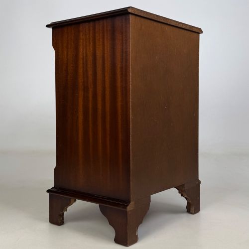 fig 3. A small mahogany chest of four drawers featuring flame grain veneer fronts, circular brass ring handles, and bracket feet.