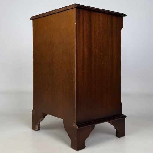 fig 5. A small mahogany chest of four drawers featuring flame grain veneer fronts, circular brass ring handles, and bracket feet.