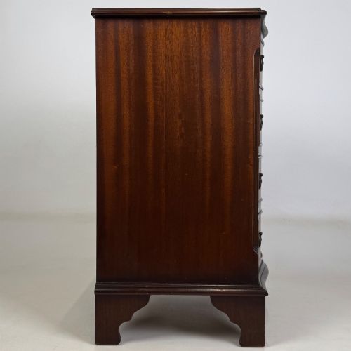 fig 6. A small mahogany chest of four drawers featuring flame grain veneer fronts, circular brass ring handles, and bracket feet.