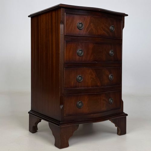 fig 7. A small mahogany chest of four drawers featuring flame grain veneer fronts, circular brass ring handles, and bracket feet.