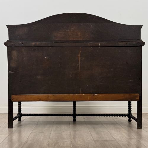 fig 5. A dark oak 19th-century sideboard featuring carved lion mask motifs, scrollwork panel doors, and bobbin-turned legs connected by stretchers.