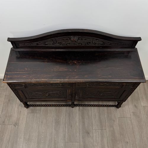 fig 9. A dark oak 19th-century sideboard featuring carved lion mask motifs, scrollwork panel doors, and bobbin-turned legs connected by stretchers.