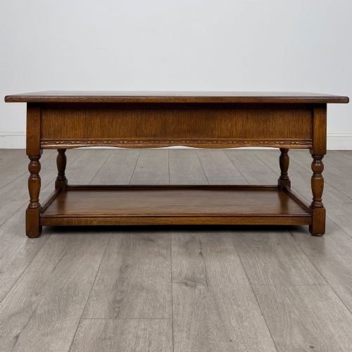 fig 4. A rectangular warm brown oak coffee table featuring two drawers with metal ring handles, carved apron detailing, turned legs, and a lower storage shelf.