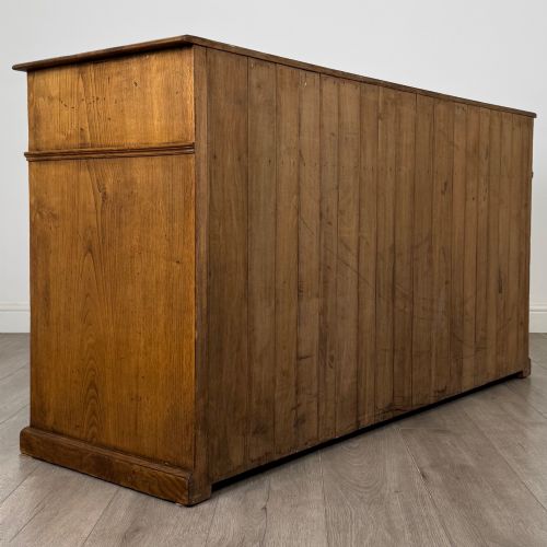 fig 4. An antique golden oak dresser base featuring three top drawers, two panelled outer doors, and a central arched open recess.