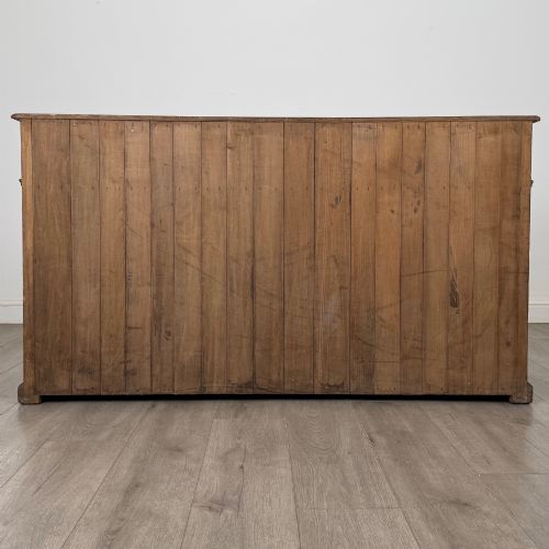 fig 5. An antique golden oak dresser base featuring three top drawers, two panelled outer doors, and a central arched open recess.