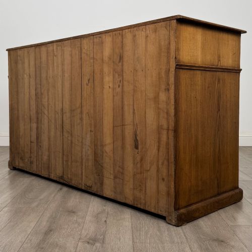 fig 6. An antique golden oak dresser base featuring three top drawers, two panelled outer doors, and a central arched open recess.