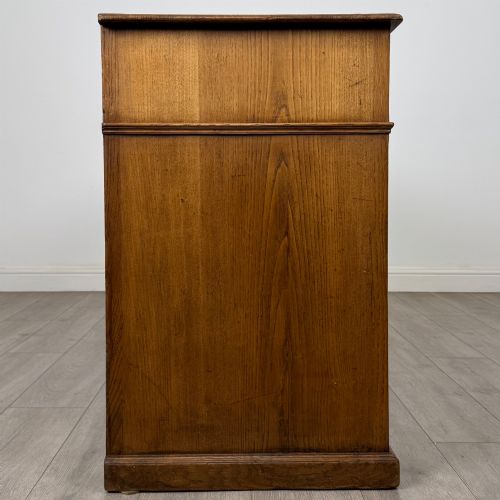 fig 7. An antique golden oak dresser base featuring three top drawers, two panelled outer doors, and a central arched open recess.