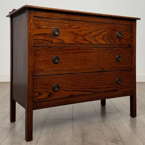 fig 7. An Edwardian oak chest of drawers featuring three full-width drawers with circular pull handles, supported by straight square legs.