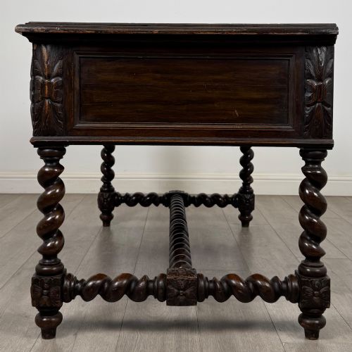 fig 2. A 19th-century dark oak writing table featuring carved drawer fronts, barley twist legs, and a low spiral stretcher.