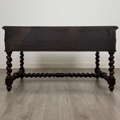 fig 4. A 19th-century dark oak writing table featuring carved drawer fronts, barley twist legs, and a low spiral stretcher.