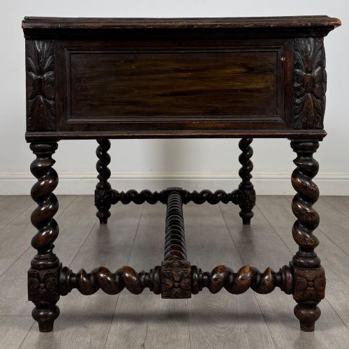 fig 6. A 19th-century dark oak writing table featuring carved drawer fronts, barley twist legs, and a low spiral stretcher.